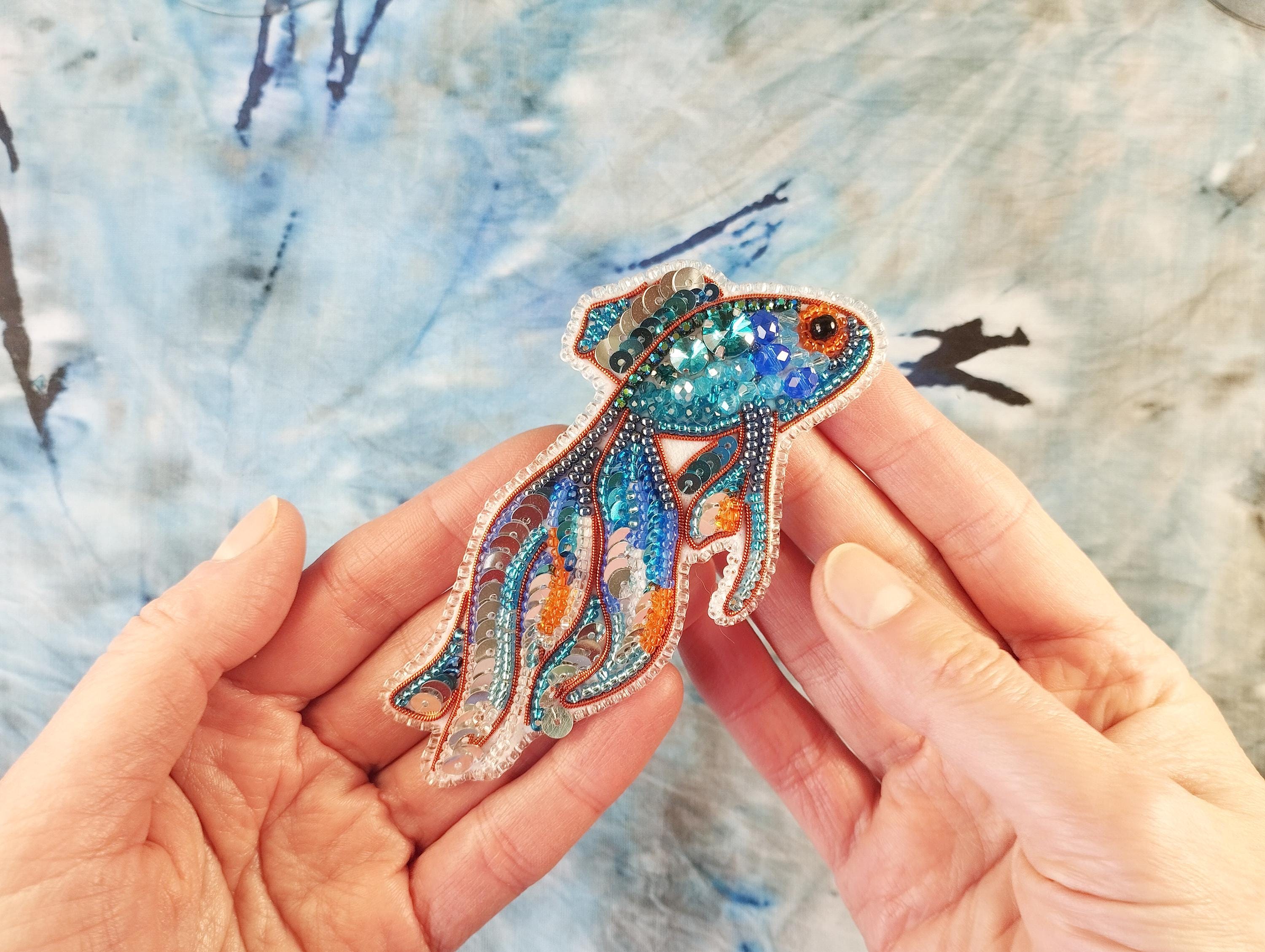 a person holding a brooch with a fish design on it